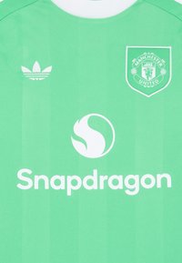 Zelena nogometna majica s bijelim akcentima, koja sadrži Adidas logo, grbManchester Uniteda, Snapdragon logo i glatku teksturu.