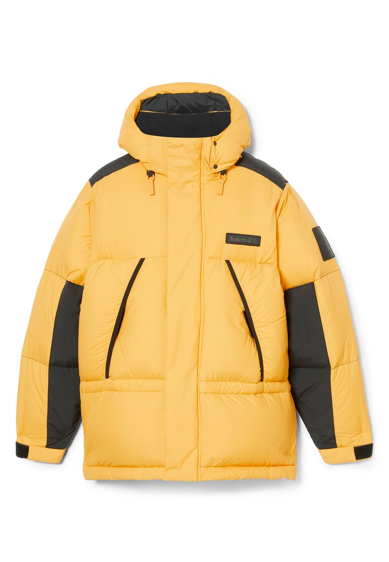 Giacca puffer gialla con accenti neri, colletto alto, tasche frontali e chiusura a zip. Presenta un logo ricamato sul petto.