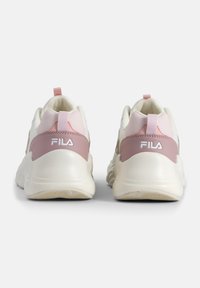 Baskets FILA blanches et roses avec un matériau lisse, une forme arrondie, une semelle en caoutchouc et un logo proéminent à l'arrière. Comprend une languette.