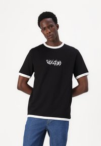 Black t-shirt with white round neckline and sleeve cuffs. Features white graphic text on the front. Made of a smooth, lightweight fabric.