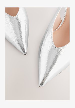 Srebrne, pęknięte lakierowane pompy z noskiem w szpic, o niskim wycięciu i gładkiej fakturze. Charakteryzują się płaską podeszwą i minimalistycznym zdobieniem.