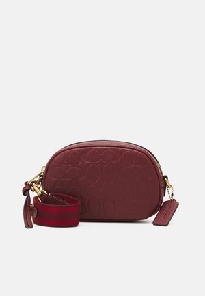 Small burgundy leather crossbody bag with embossed logo pattern, gold hardware, detachable wide strap with red stripes, and leather tag.