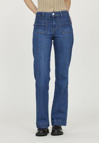 Jean en denim bleu avec une coupe droite, un design à cinq poches, des coutures visibles et une fermeture à bouton à la taille. Texture lisse.