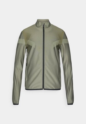 Jachetă sport de culoare verde măslin cu fermoar frontal, guler în picioare, design texturat, accente negre și mâneci lungi. Prezintă o siluetă ajustată.