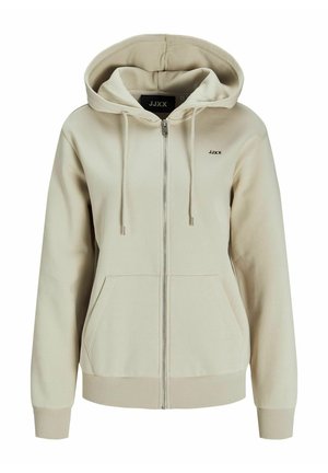 Sudadera beige con cremallera, capucha con cordón, bolsillos frontales, puños de canalé y un pequeño logo en el lado izquierdo del pecho. Textura de tela suave.