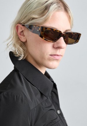 Tortoiseshell sunglasses with a rectangular frame and dark lenses. The temple features subtle branding and a glossy finish.