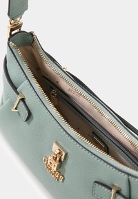 Miętowo-zielona skórzana torebka z złotymi okuciami, wyposażona w wnętrze na zamek błyskawiczny, liczne przegrody oraz teksturowane wykończenie zewnętrzne.