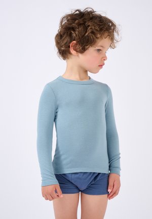 Camisa de manga larga azul claro hecha de una tela suave, con cuello redondo y mangas ajustadas, combinada con pantalones cortos azul oscuro.