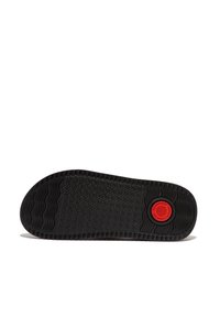 Zwarte rubberen schoenzool met een gestructureerd oppervlak, met een cirkelvormig rood logo op de hak en golvende looppatronen voor grip.