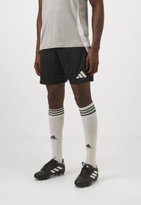 Lys grå sports skjorte, sorte shorts med hvide accenter, hvide sokker med sorte striber, sorte fodboldstøvler med hvide striber.