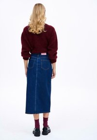 Džínová sukňa v tmavomodrej farbe, po členky, s zadnými vreckami a rovnými švami. V parádne skombinovaná s burgundským svetríkom a čiernymi platformovými topánkami.