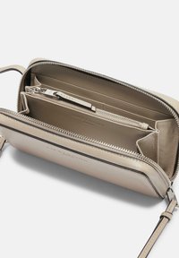 Borsa in pelle beige chiaro con chiusura a cerniera, diversi scomparti interni e una cerniera con accentuazione in argento. Texture liscia con cuciture a contrasto.