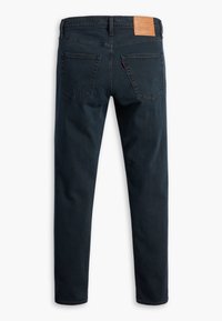 Ciemnoniebieskie dżinsy o prostym kroju, wykonane z denimu. Posiadają brązową skórzaną łatę w talii, dwie tylne kieszenie oraz czyste linie.