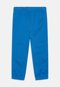 Pantalon de survêtement en coton bleu avec une taille élastique, des poignets ajustés et une surface lisse et texturée. Aucun motif ni détail supplémentaire visible.
