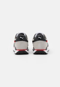 Gray and black sneakers with a suede texture, featuring red accents, white soles, and a distinctive heel design.