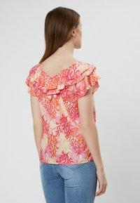 Korte mouwen blouse in het roze met koraalrifpatroon, met gefronste halslijn en rugdetail, gemaakt van een lichte stof.