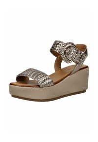 Sandali wedge con cinturino intrecciato metallico e piattaforma beige chiaro, caratterizzati da un accento a fibbia rotonda sul cinturino alla caviglia.