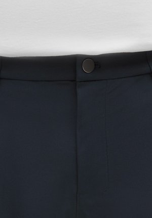 Tmavě modré kalhoty s hladkou texturou, zavíráním na knoflík vpředu a na míru šitou pasovou částí s viditelnými detaily stehu.