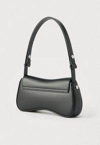Borsa a spalla in pelle nera liscia con fondo curvo e tracolla regolabile fissata da borchie argentate su sfondo chiaro.