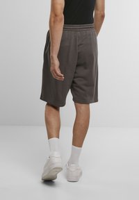 Gray, knee-length shorts in soft fabric with an elastic waistband. Paired with white sneakers and ankle-length socks.