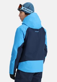 Heren kleurblok skijas in marineblauw en lichtblauw, met een capuchon, ritsen en een gladde, waterdichte stof.