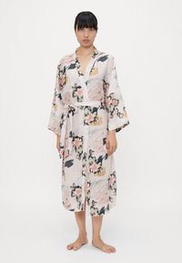 Kimono w kwiatowy wzór, wykonany z lekkiego materiału; ma długie rękawy, pasek w talii i otwarty przód. Kolory to delikatny róż i czerń.