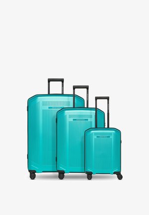 Tres maletas rígidas turquesas de diferentes tamaños con asas telescópicas negras extendidas y cuatro ruedas cada una.