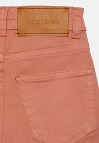 Calças de ganga rosa com um rótulo de cintura em pele embutido com "cost:bart" e um bolso traseiro com costura decorativa.