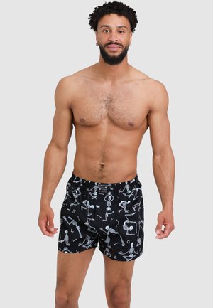 Schwarze Badehosen mit einem verspielten Skeletontdesign, elastischem Bund und lockerer Passform. Hergestellt aus leichtem, atmungsaktivem Stoff.