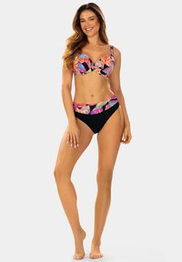 Zestaw bikini z czarnym dołem, kolorowym topem w liściasty wzór z wsparciem w postaci fiszbin oraz wysokim stanem dolnej części, który ma podobne akcenty.