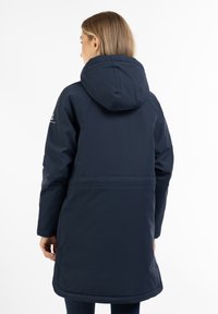 Marineblå lang frakke med hætte, der har en vandafvisende overflade, glat tekstur og en lige pasform, der slutter ved midten af låret, med skjulte lommer.