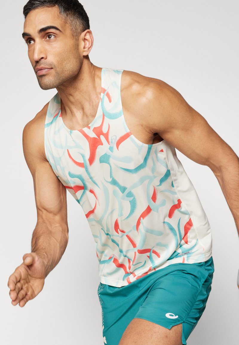 Camiseta deportiva sin mangas de tela ligera que presenta un patrón en espiral rojo y azul sobre un fondo crema; combinada con pantalones cortos en azul verdoso con acentos.