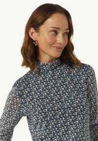 Langarm, hoge hals top met een geometrisch patroon in blauw, crème en zwart. Gemaakt van een soepele, lichte stof met een getailleerde pasvorm.