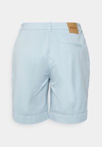 Light blue shorts made of soft fabric, featuring a brown leather label with "BOSS" at the waistband and a single back pocket.