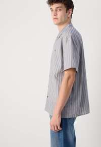 Korte ermer skjorte med knapper i grått med vertikale svarte striper, laget av lett stoff, med en camp-krage og en avslappet passform.