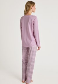Lichtpaarse blouse met lange mouwen, gecombineerd met losse, gebloemde pyjamabroeken in het roze met cirkelmotieven. Zacht materiaal met een ontspannen pasvorm.