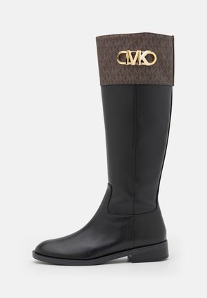 Botte haute en cuir noir avec un revers marron à motif et un logo doré "MK" sur la tige supérieure, talon plat et bout arrondi.