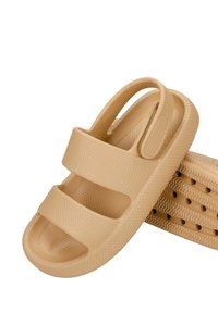 Beige rubberen sandalen met drie brede banden, open hiel, gestructureerd oppervlak en ventilatiegaten in de zool. Lichtgewicht en flexibele ontwerpen.