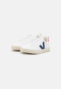Sneaker bianche con una texture perforata, dettagli blu navy e ganci rossi sul tallone. Presentano una chiusura con lacci e suole in gomma beige.