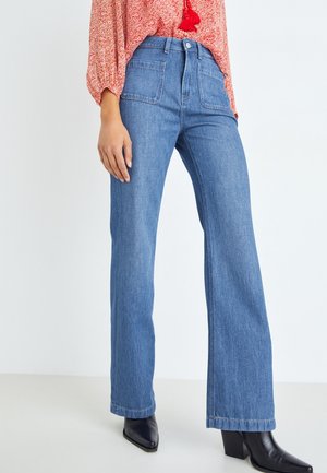 Jean bleu clair taille haute avec une coupe décontractée et jambes larges, doté de deux poches avant. Le tissu a une texture douce ; l'ourlet est légèrement effiloché.