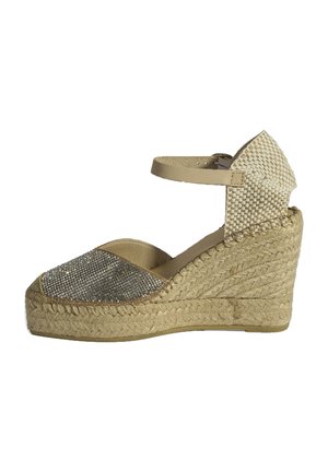 Beige espadrille wedge schoen met een sprankelende zilveren neus, een geweven stoffen achterkant en een enkelbandje. Jute tussenzool met textuurdetails.