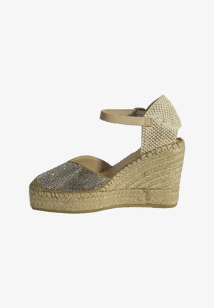 Beige espadrille wedge schoen met een sprankelende zilveren neus, een geweven stoffen achterkant en een enkelbandje. Jute tussenzool met textuurdetails.