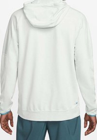 Hellgrauer Kapuzenpullover mit glatter Textur. Verfügt über eine Kängurutasche, gerippte Bündchen und ein blaues Nike-Logo am Saum.