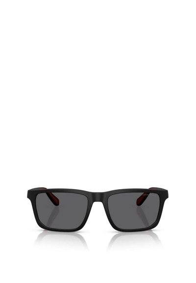 Lunettes de soleil rectangulaires noires avec des lentilles teintées foncées, finition mate et accents rouges sur les branches. Design bicolore avec une texture douce.