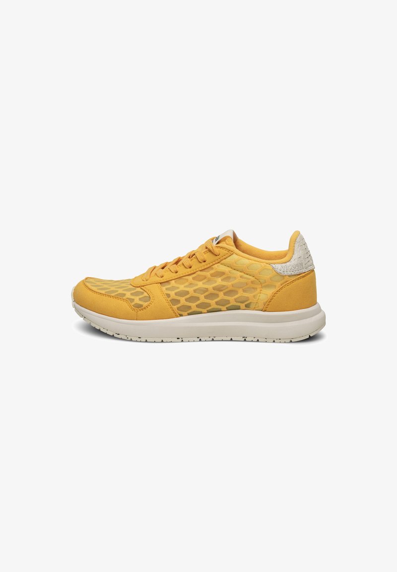 Yellow athletic shoe featuring a mesh design with hexagonal patterns, suede overlays, and a white rubber sole. Lace-up front and textured heel.
