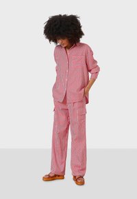 Red and white striped shirt and pant set in lightweight fabric, featuring a pocket on the shirt, loose fit, and wide-leg trousers.