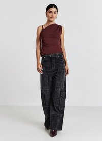 Haut bourgogne à une épaule associé à un pantalon cargo en denim noir avec poches et une coupe large. Tissu lisse avec une finition texturée.