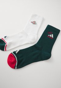 Two socks: one white with a small red and green graphic, and one dark green with red accents and a white logo. Both have ribbed texture.