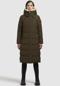Długi, oliwkowozielony płaszcz puchowy z kapturem, z zapięciem na zamek z przodu, pionowym pikowaniem oraz bocznymi kieszeniami. Wnętrze wykończone teksturowanym sztucznym futrem.