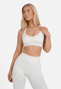 Witte sportbeha en high-waisted leggings, gemaakt van een textuurstof met stretch, met subtiele logo-accenten op beide stukken.